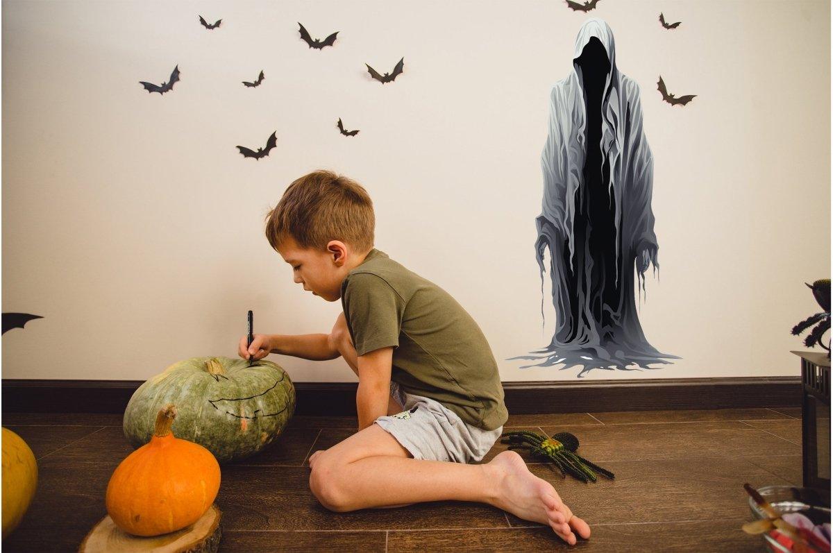 Child carving pumpkins alongside a sinister shadow wall sticker for Halloween decor.