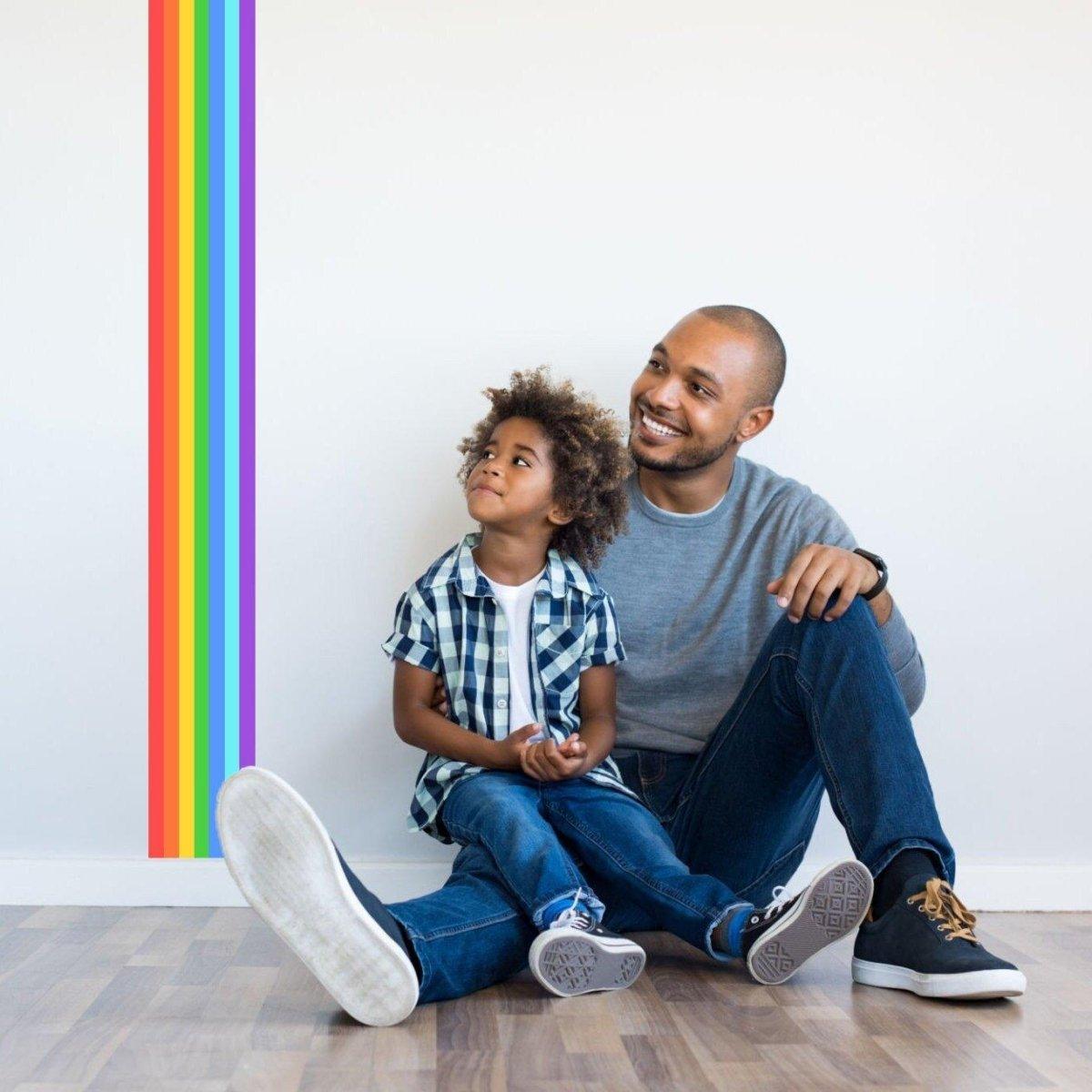 Father and son enjoying time together next to a rainbow stripe sticker on a wall, adding color to the space.