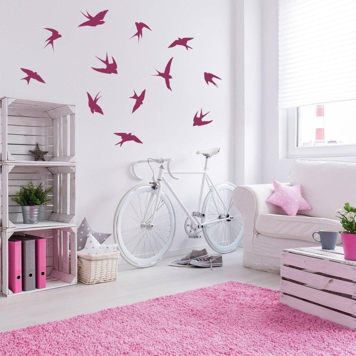 Flock of bird wall decals in a stylish living room with a bicycle and pink decor.