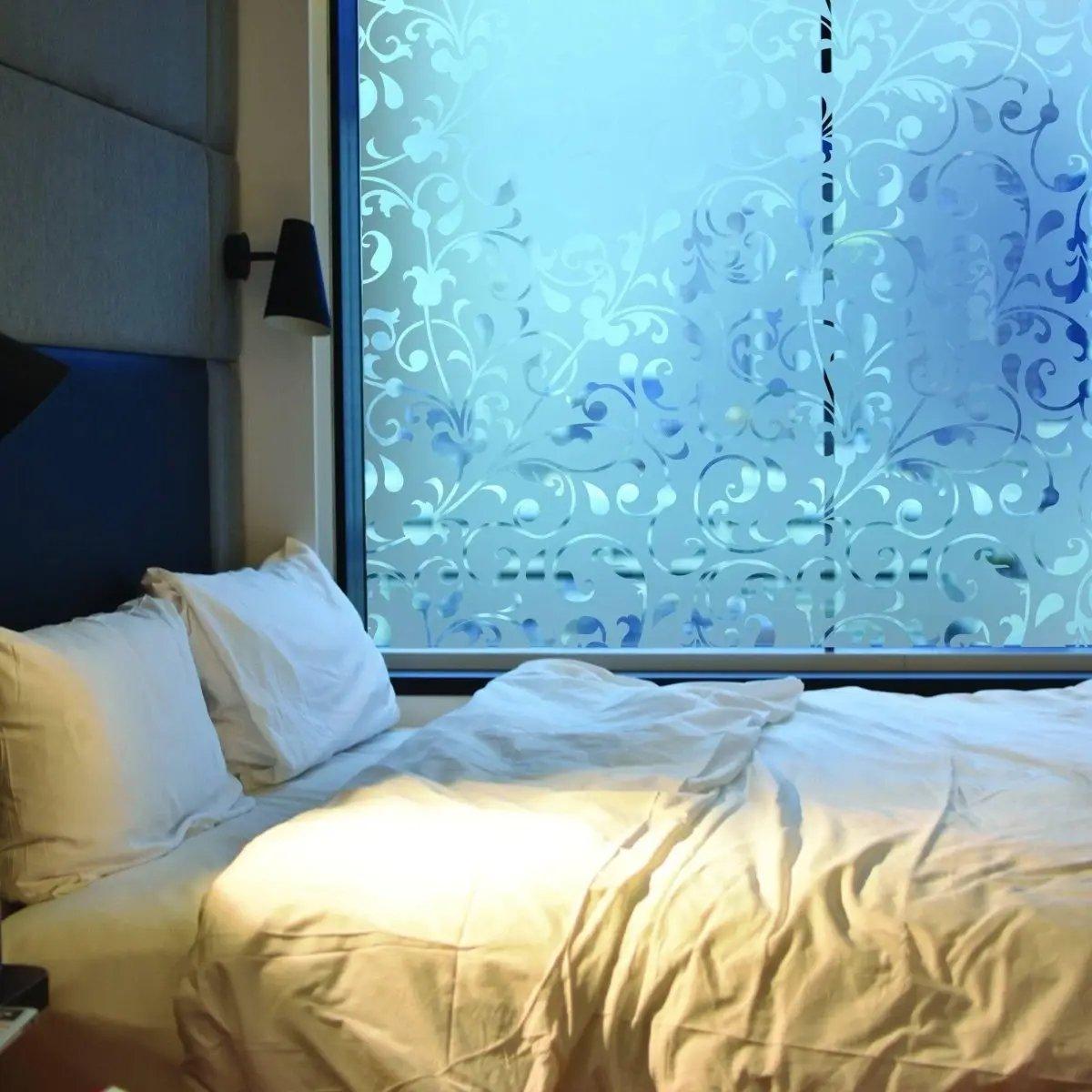 Frosted window film with decorative floral patterns, adding privacy and style to a bedroom setting.