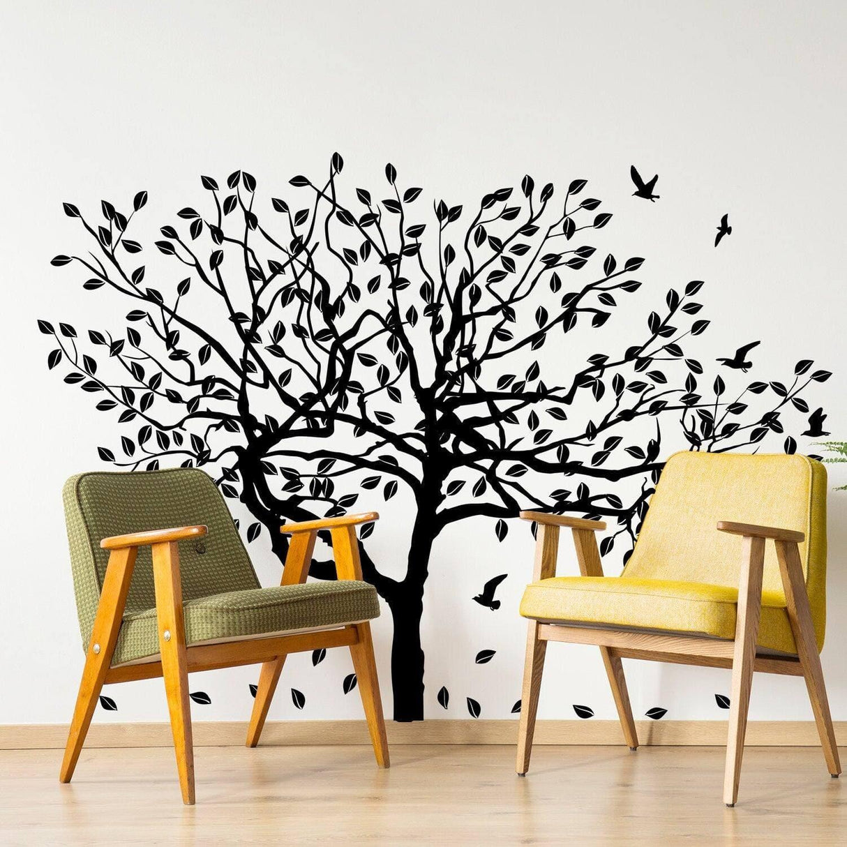 Black tree wall decal with leaves and birds, enhancing home decor, paired with stylish chairs.