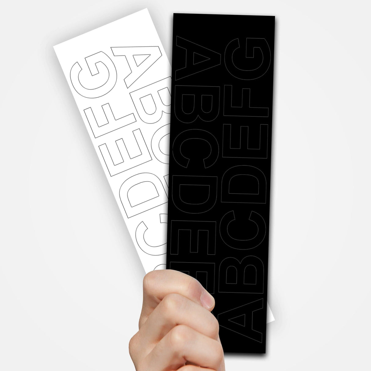 Hand holding two sets of removable vinyl letter decals in black and white for versatile lettering options.