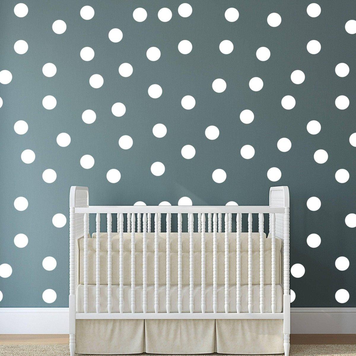 Colorful 2-inch round dot wall stickers on a gray wall behind a white crib, adding creativity to a nursery.