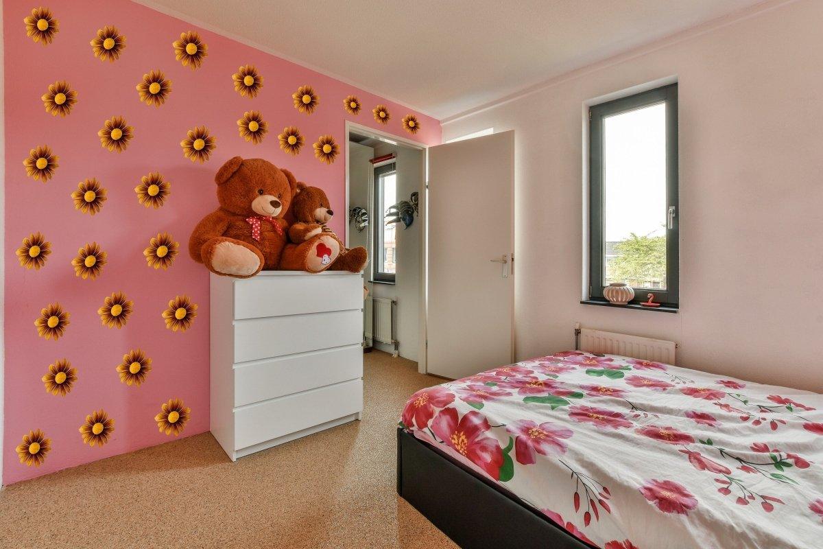 Cozy bedroom featuring Boho Daisy wall stickers, floral bedding, and teddy bears on a vibrant pink wall.
