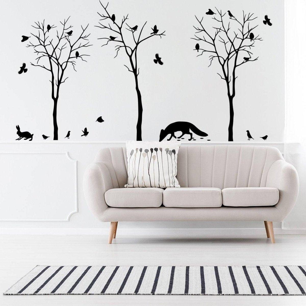 Botanical wildlife vinyl decal set featuring tree silhouettes, birds, and animals above a modern sofa in stylish interior.