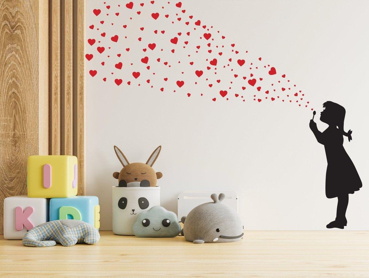 Girl silhouette blowing heart bubbles on a wall with colorful toys in a playful room setting.