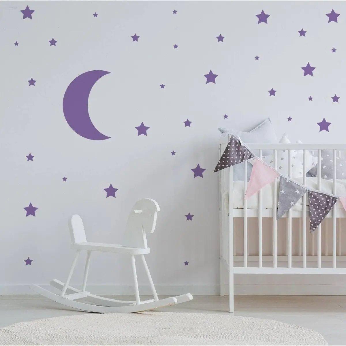 Purple moon and star wall decals in a child's nursery with a rocking horse and crib.