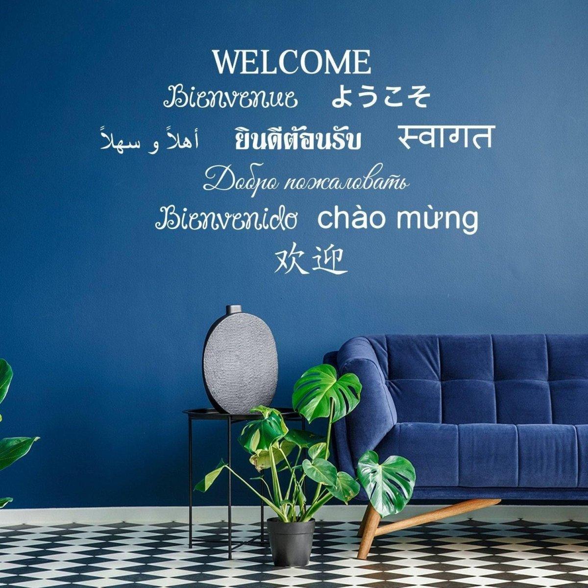 Wall decals displaying the word 'WELCOME' in multiple languages on a blue wall, paired with stylish furniture.
