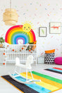 Colorful nursery with vibrant rainbow wall decal, sunny design, and playful decor for a joyful atmosphere.