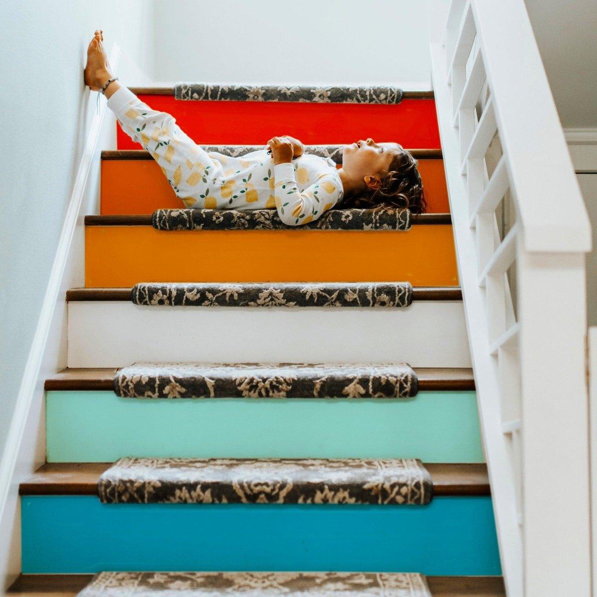 Child lying on colorful stairs with self-adhesive gradient risers, showcasing vibrant transformation kits.