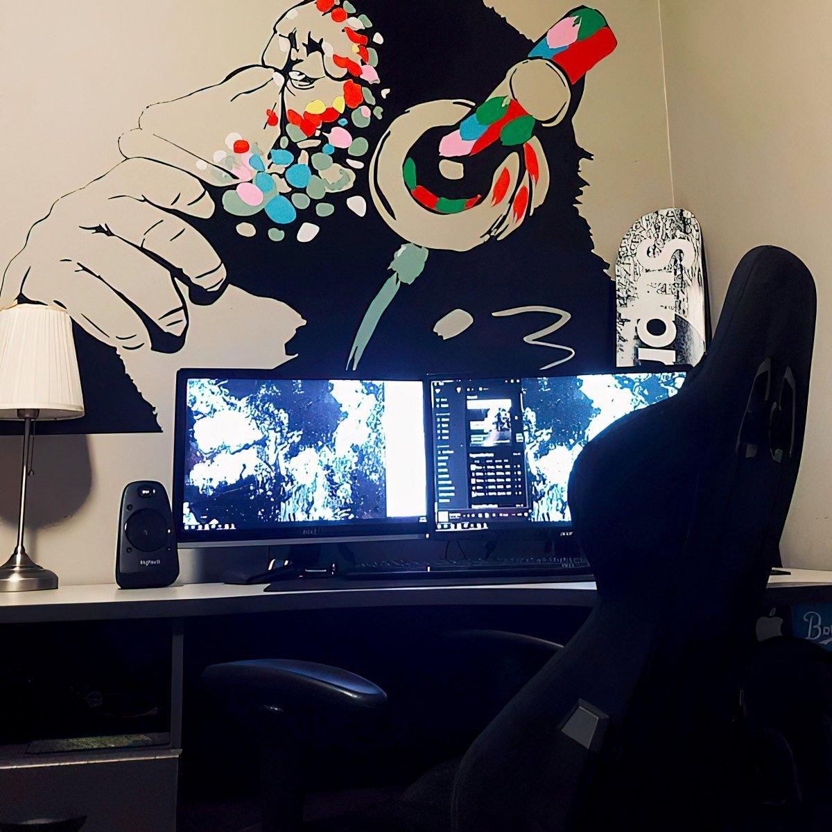 Contemplative monkey wall decal with headphones above dual computer monitors in stylish kids room