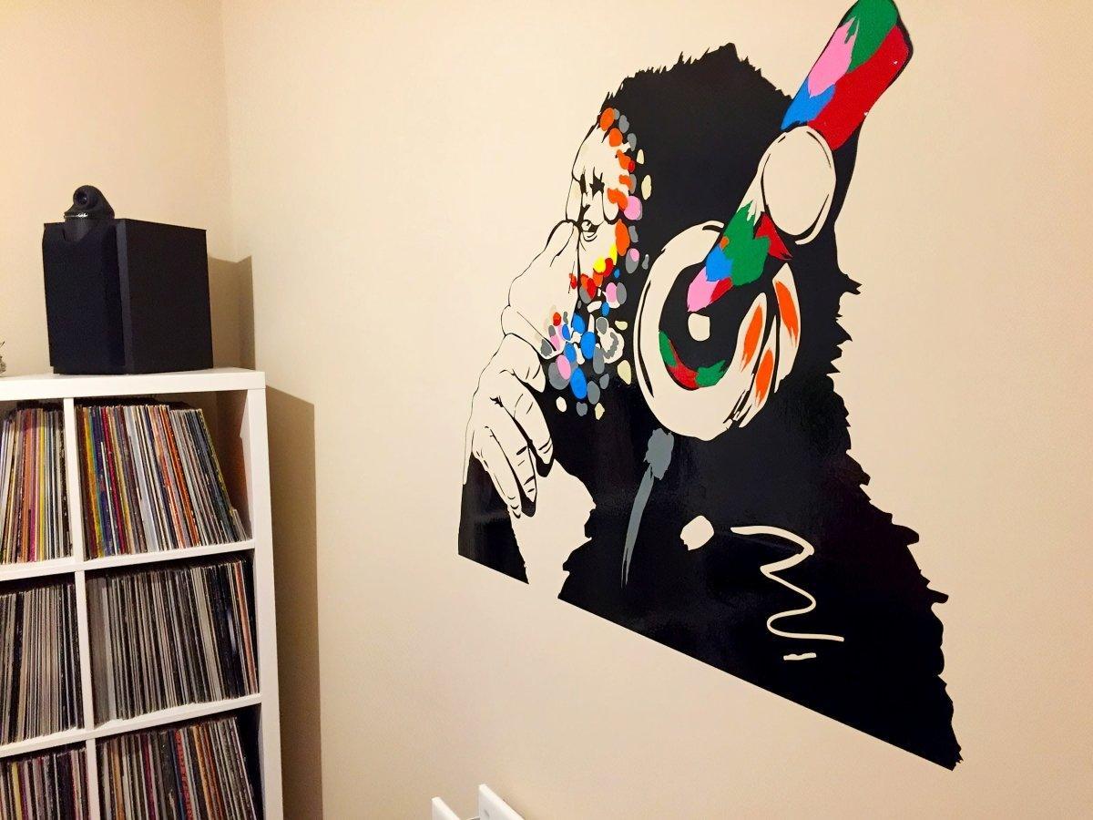 Contemplative monkey wall decal with colorful headphones, perfect for kids' room or music-themed decor.
