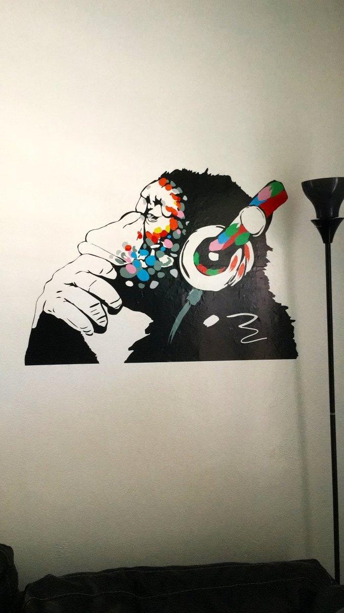 Contemplative monkey wall decal wearing headphones, perfect for kids room decoration and music lovers.