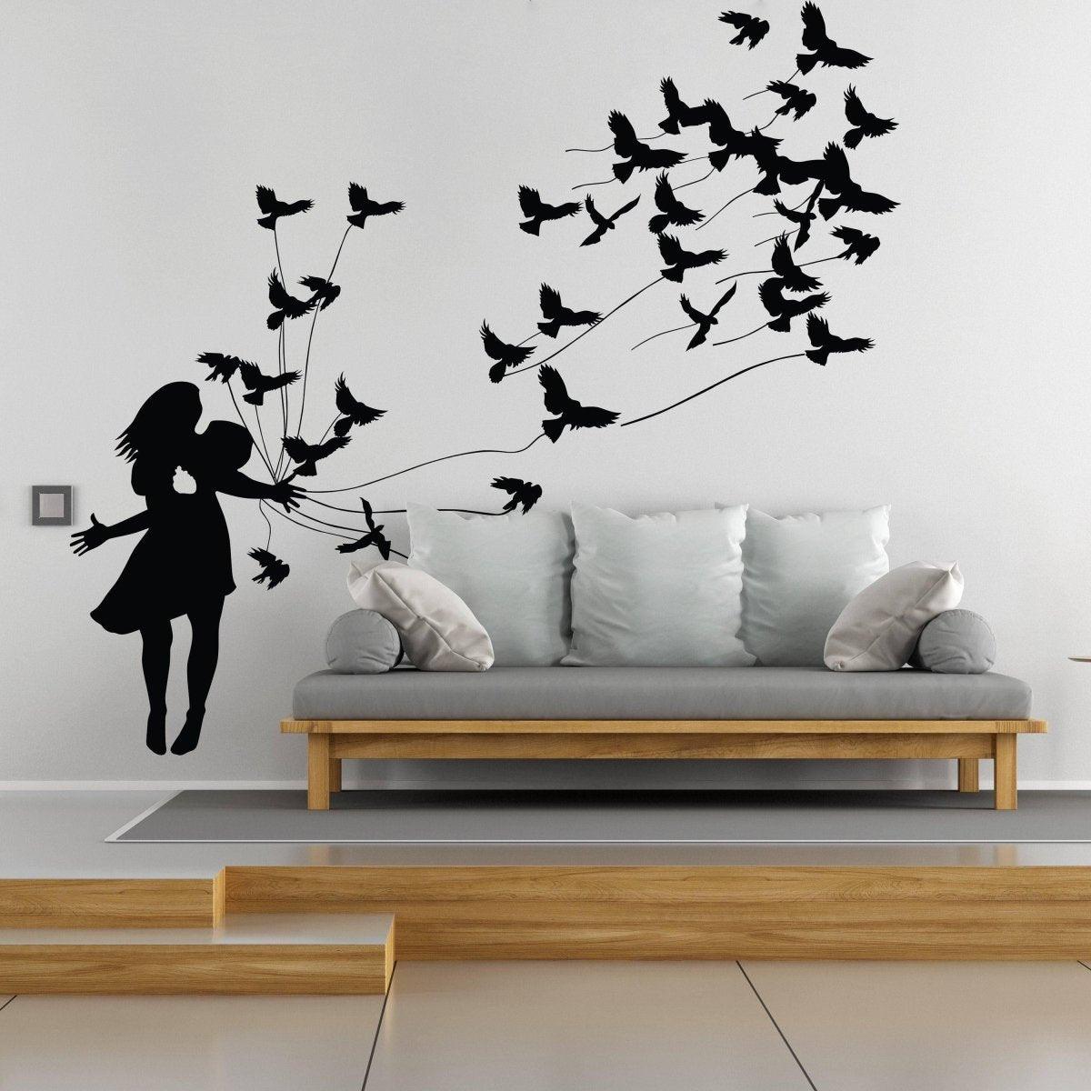 Expressive Banksy wall sticker of a girl releasing birds above a modern sofa in a stylish living room.