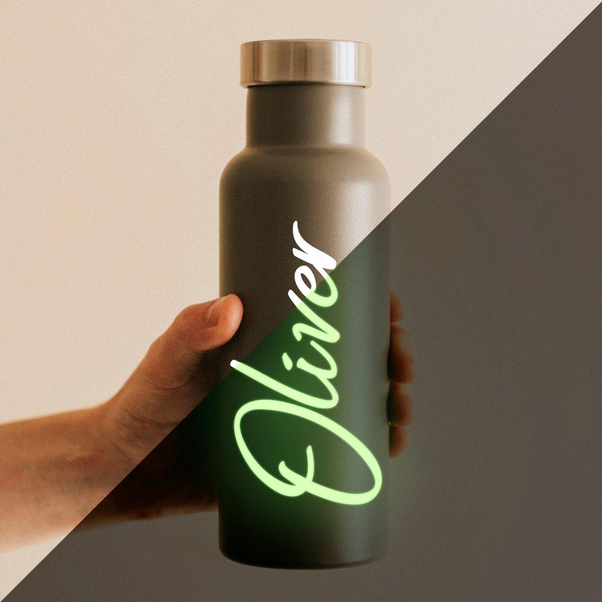 Personalized glow-in-the-dark name decal on a water bottle held by a hand.