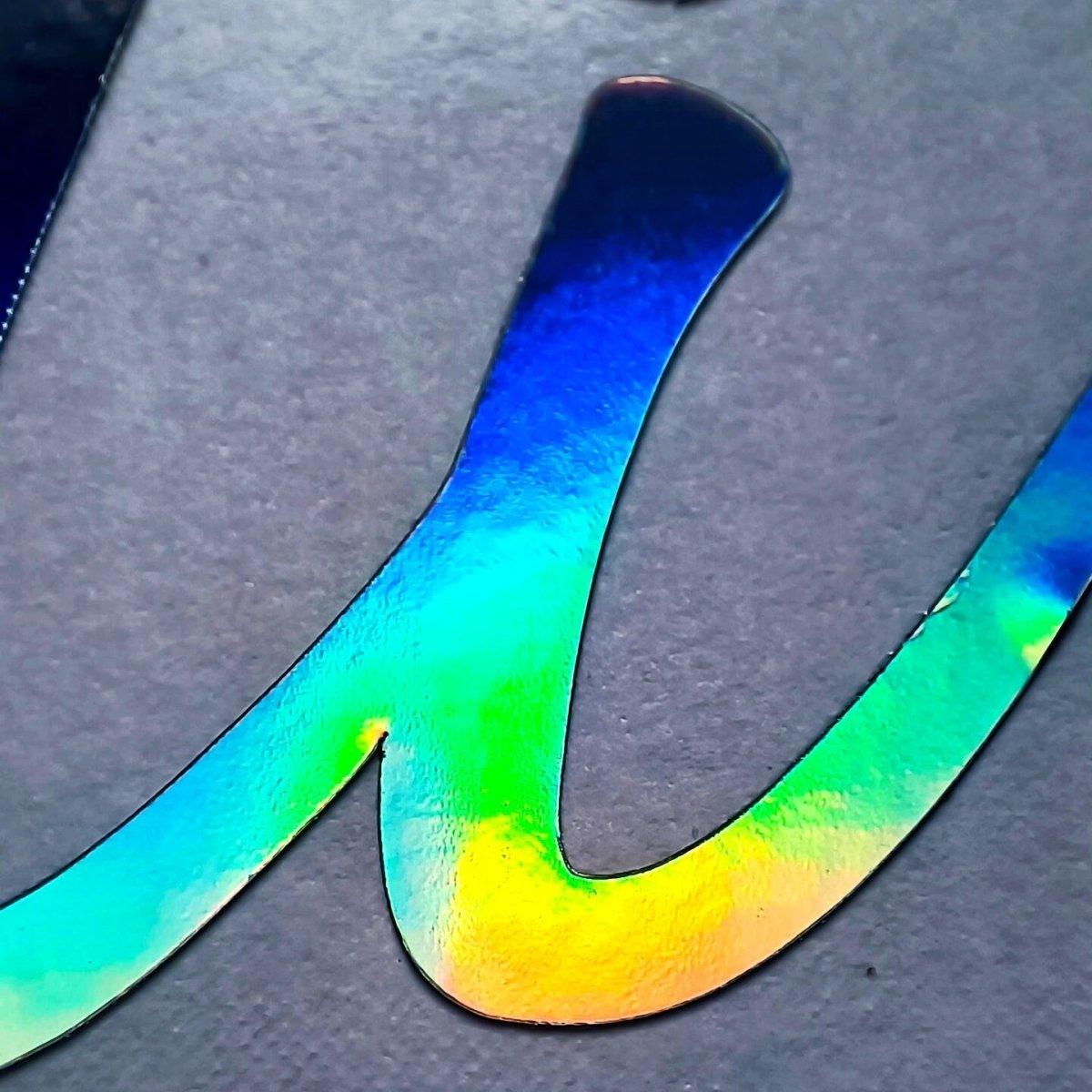 Close-up of vibrant rainbow holographic vinyl decal showcasing colorful reflections and smooth finish.