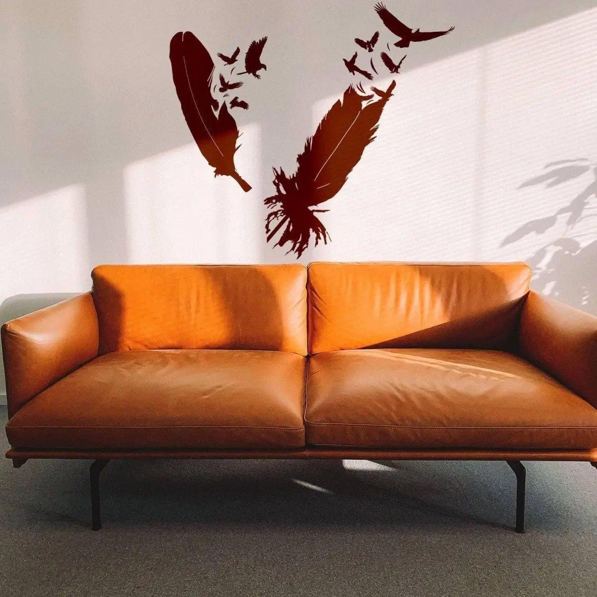 Stylish bird and feather wall sticker above a modern brown leather sofa, perfect for home decor.