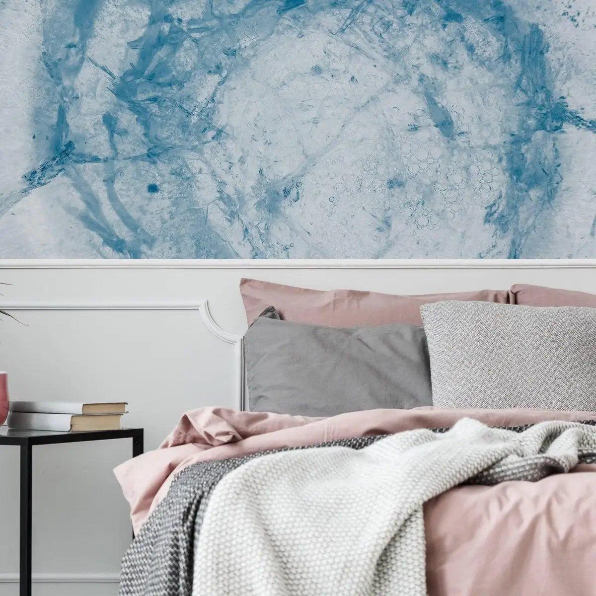 Sophisticated blue marble effect wallpaper in a cozy bedroom setting with soft bedding and decor.
