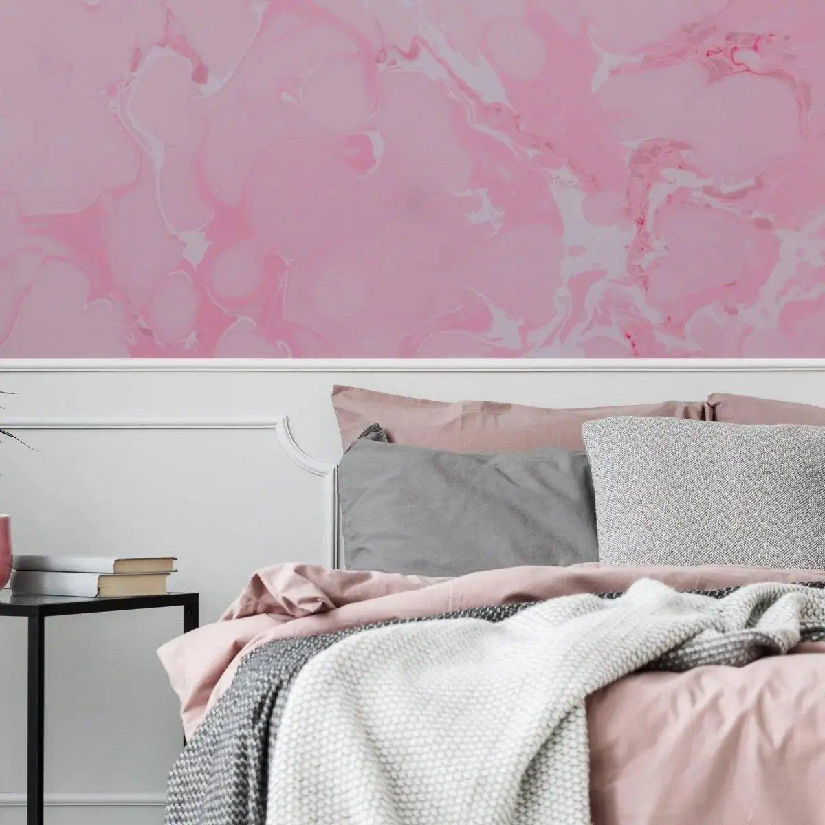 Elegant pink marble wallpaper accent in a cozy bedroom with stylish bedding and side table.