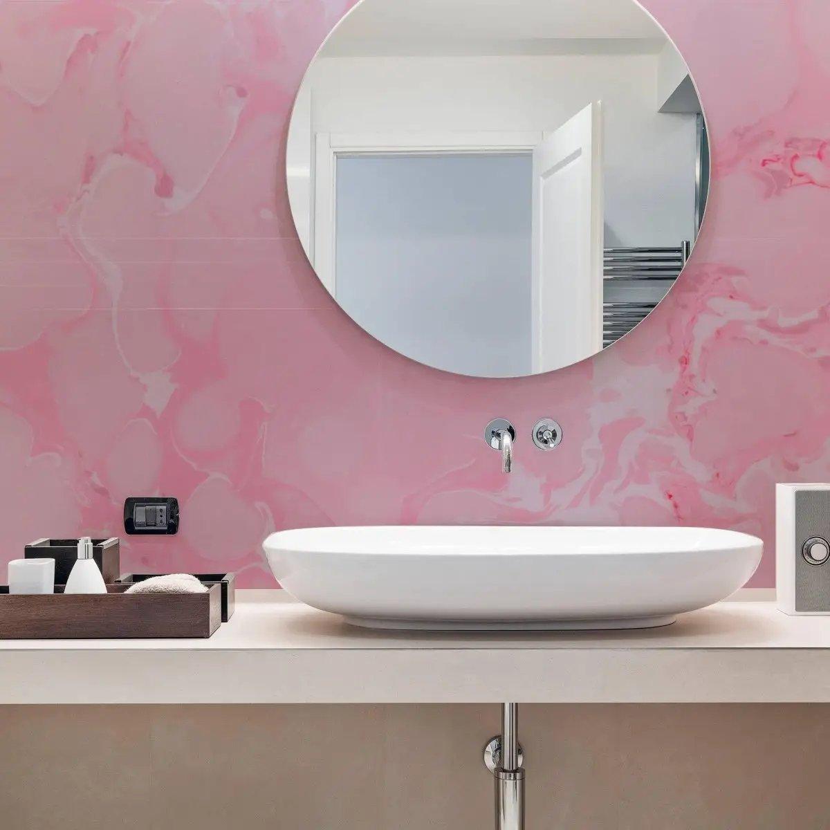 Elegant pink marble wallpaper in a modern bathroom with white sink and round mirror.