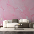 Elegant pink marble wallpaper accent wall behind modern furniture and coffee table in a cozy living room setting.