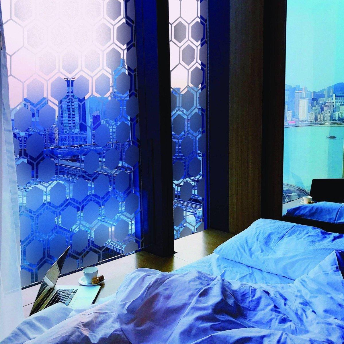 Stylish frosted window film enhancing privacy and aesthetics in a modern bedroom overlooking a cityscape.