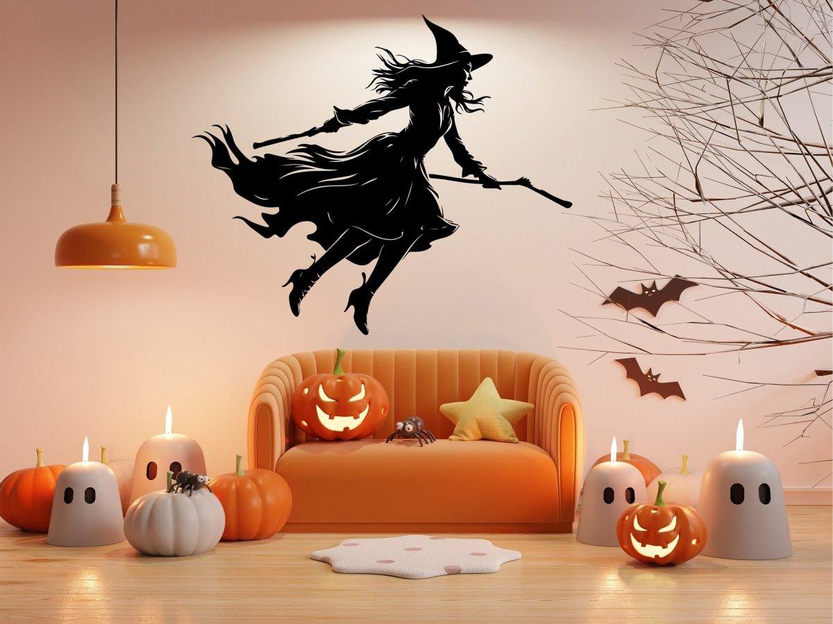 Halloween witch broom decal silhouette on living room wall, adorned with pumpkins and spooky decor.