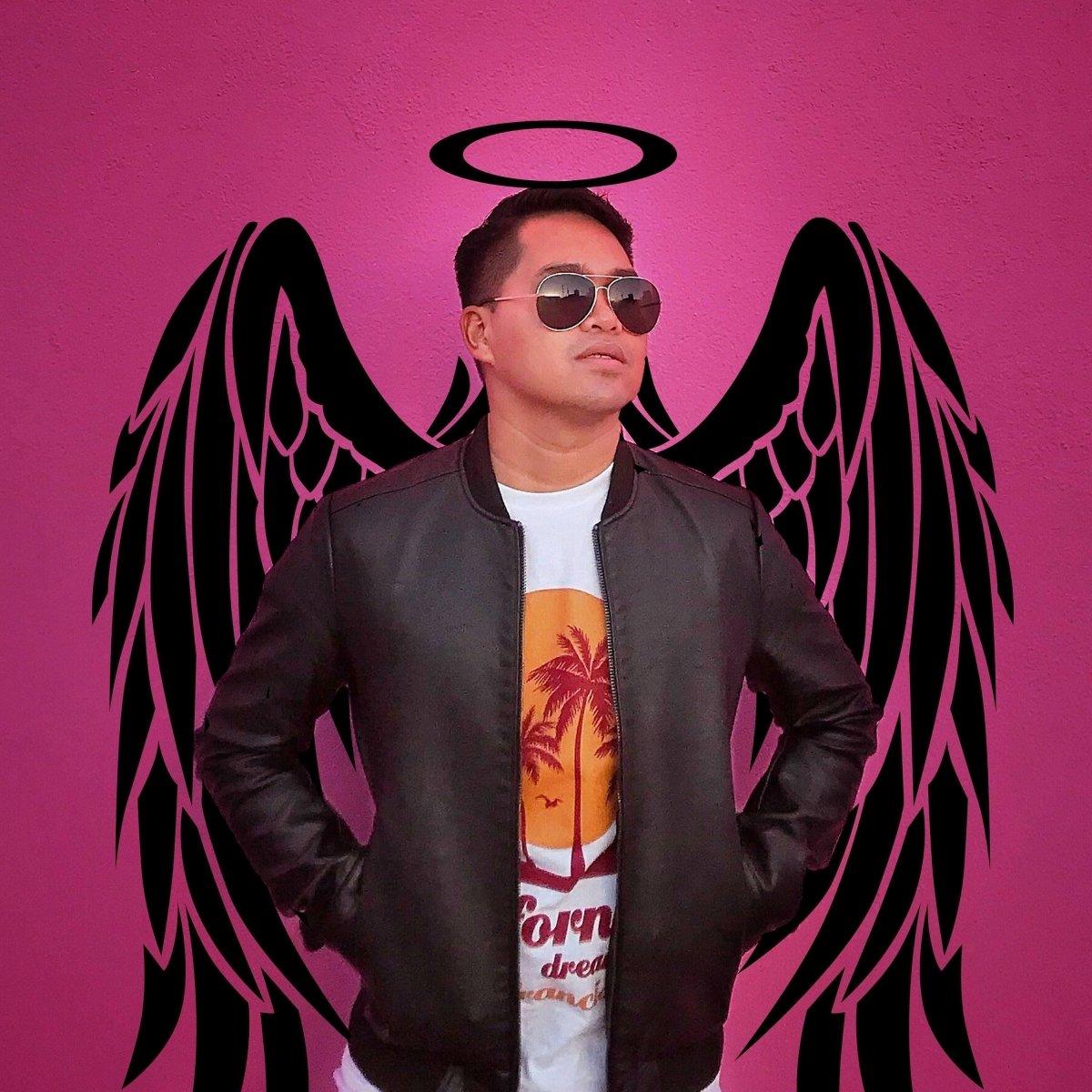 Person wearing sunglasses and a leather jacket in front of pink wall with angel wings mural.