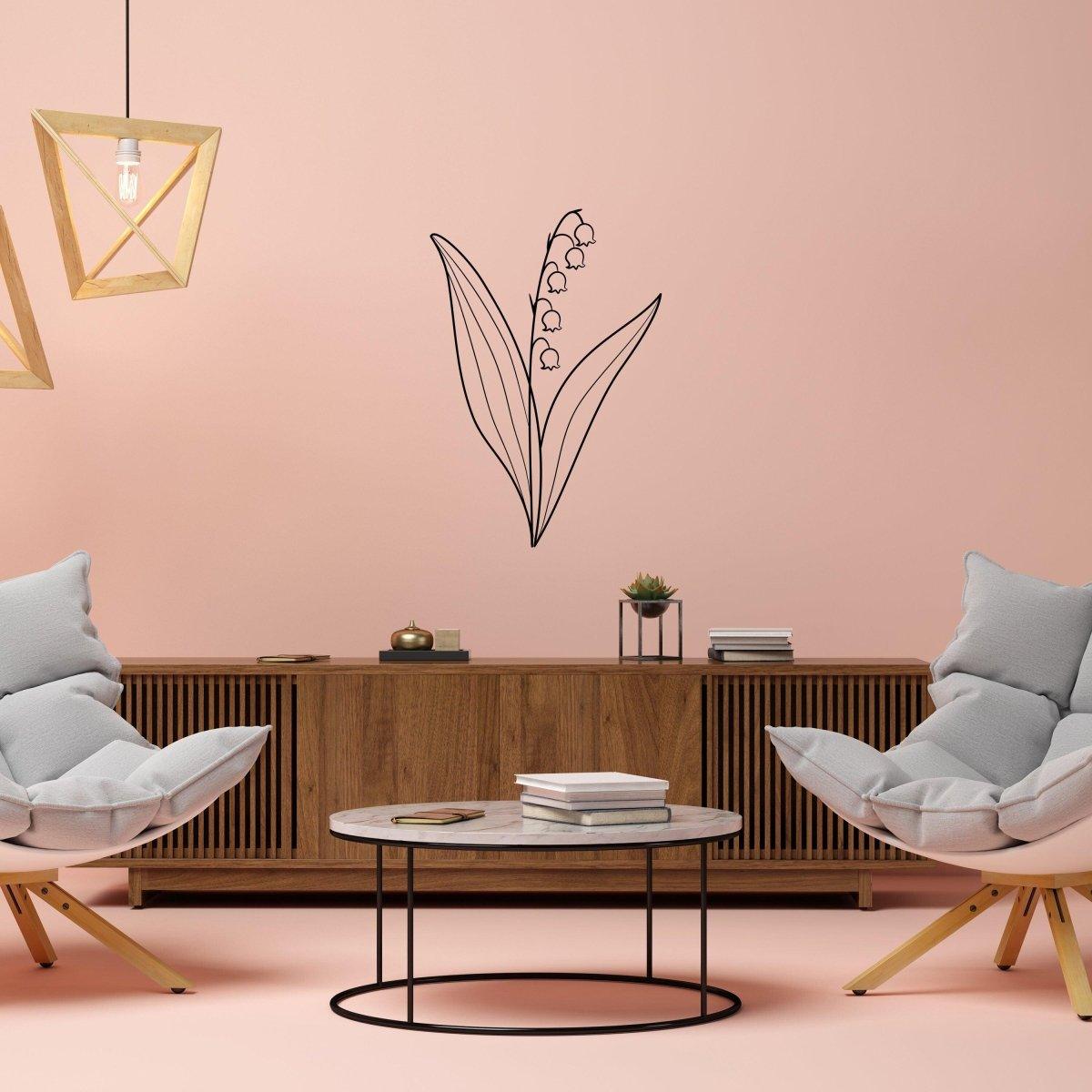 Minimalist black lily of the valley wall decal on pastel pink wall in modern living room with stylish furniture.