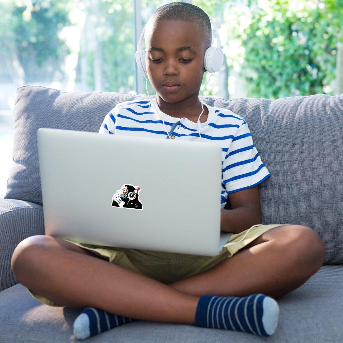 Child with headphones using a laptop featuring a playful monkey vinyl decal sticker.