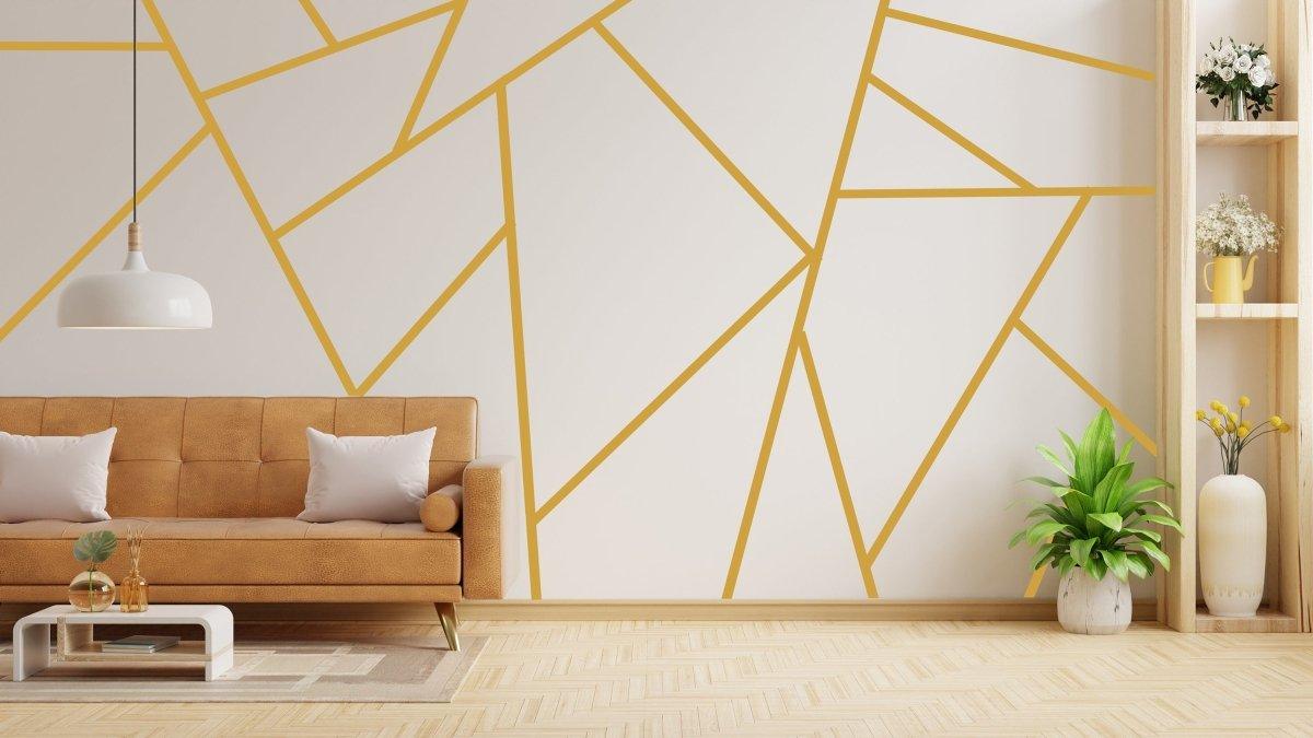 Elegant geometric gold wall stickers in a modern living room with a brown sofa and decorative plants.
