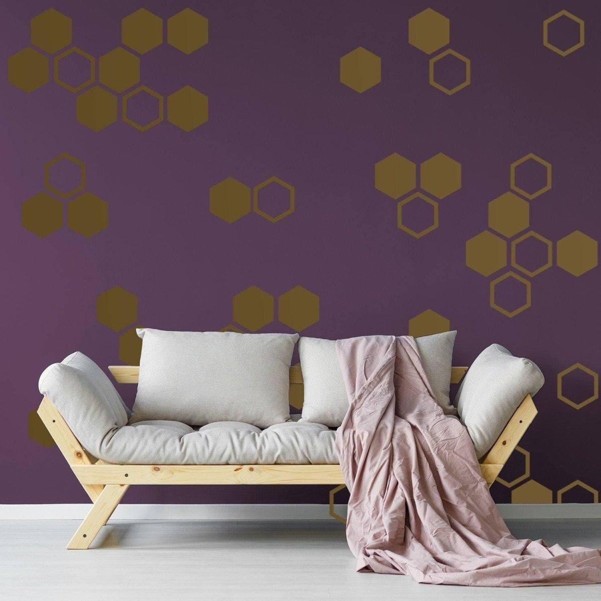 Elegant geometric hexagon wall decals in gold on a purple background, enhancing cozy living space with soft couch.