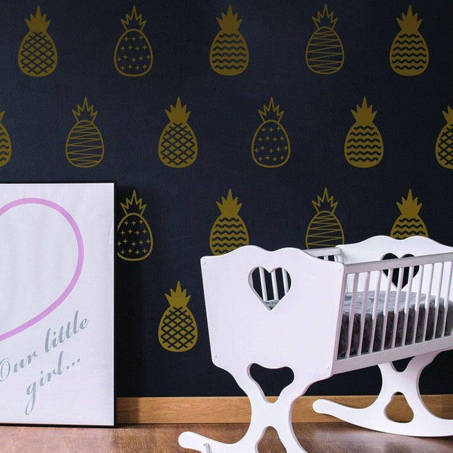 Stylish golden pineapple wall decals on a black wall, featuring a cute nursery with a white crib and heart design.