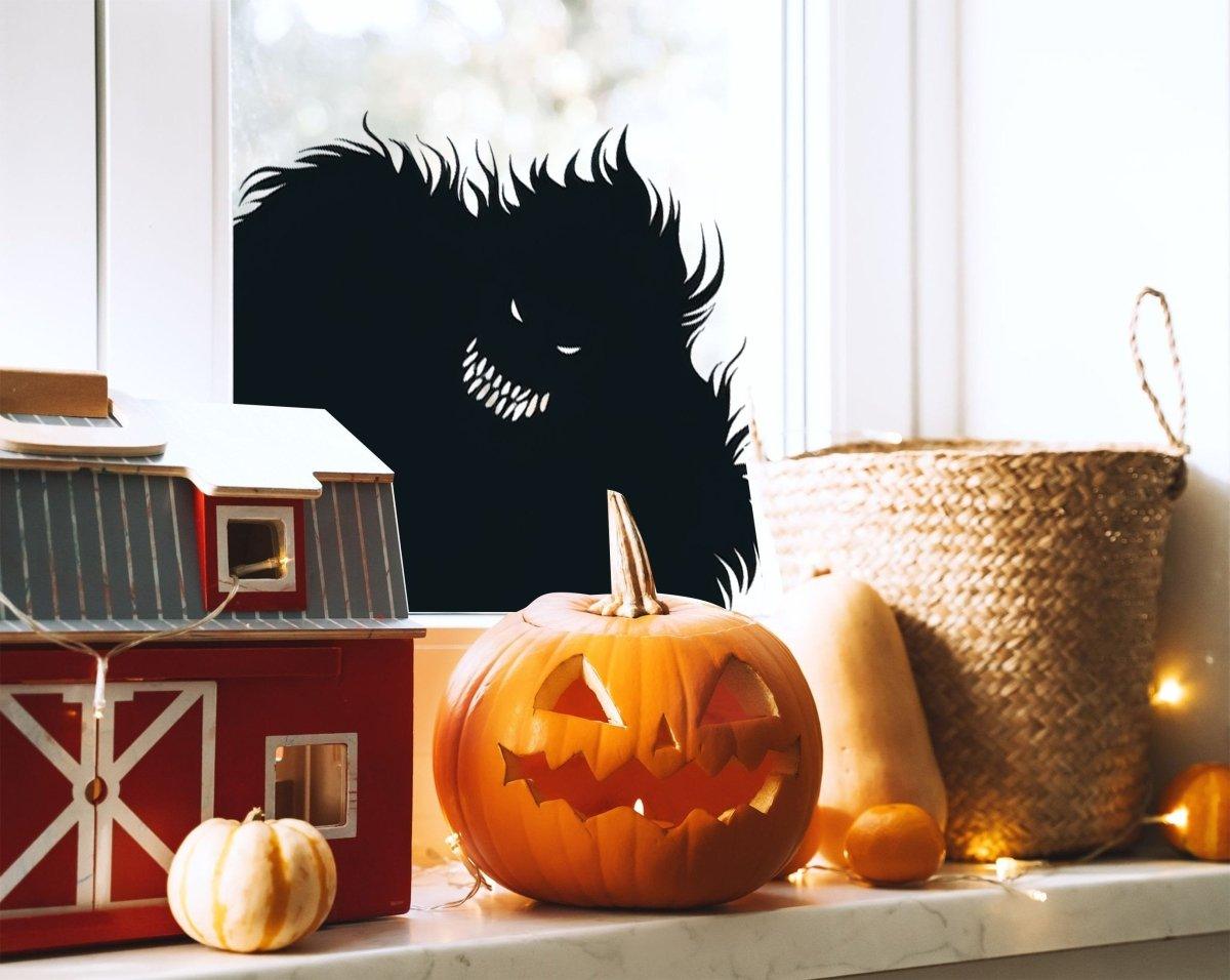 Spooky monster silhouette vinyl decal in window with Halloween decorations, pumpkin, and toy barn.