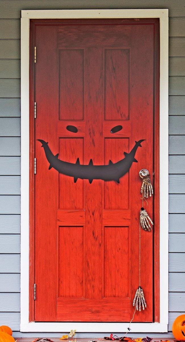 Halloween monster face door decal with a spooky smile on a red door, perfect for festive decorations.