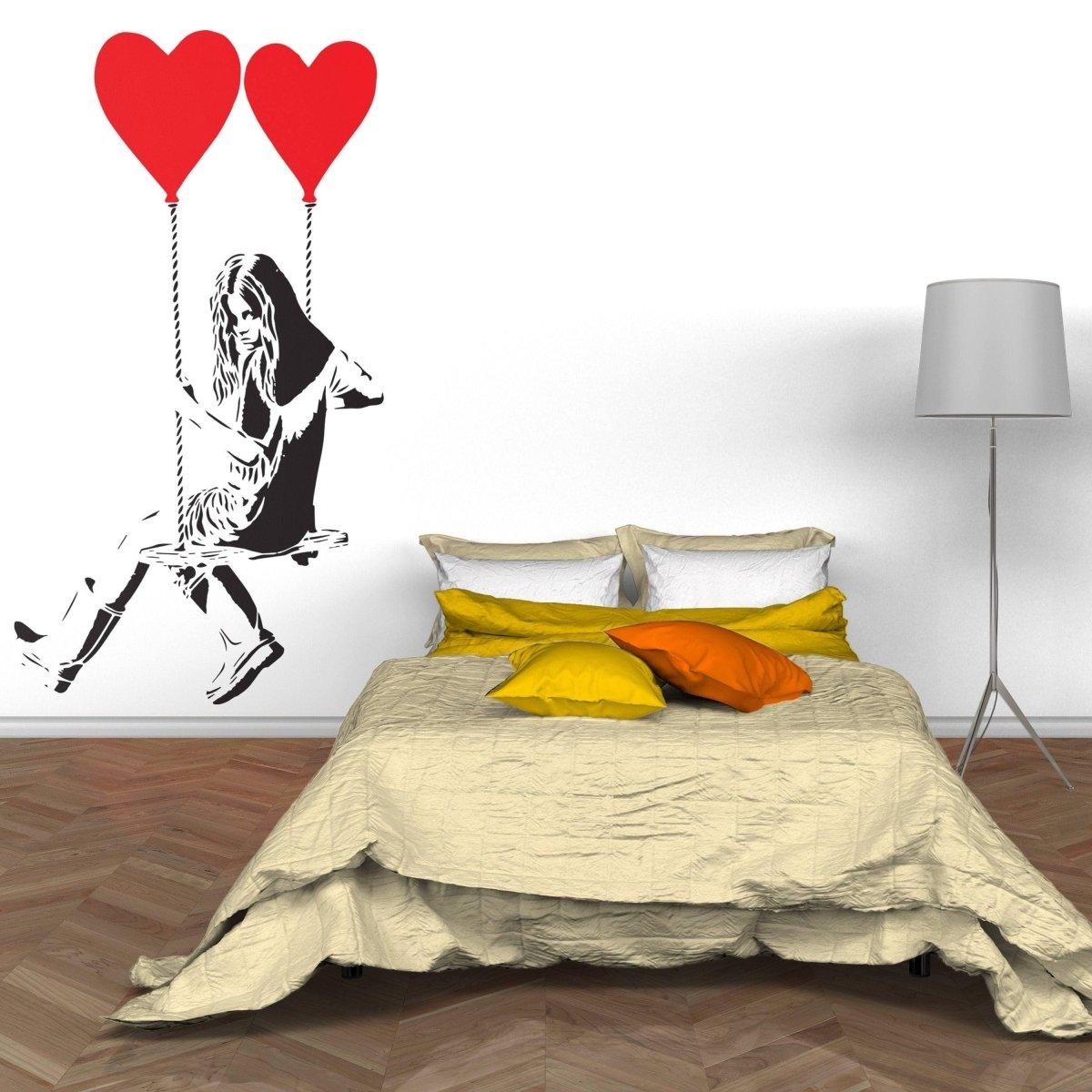 Vinyl heart balloon wall decal in a cozy bedroom, featuring a girl swinging with red heart balloons.