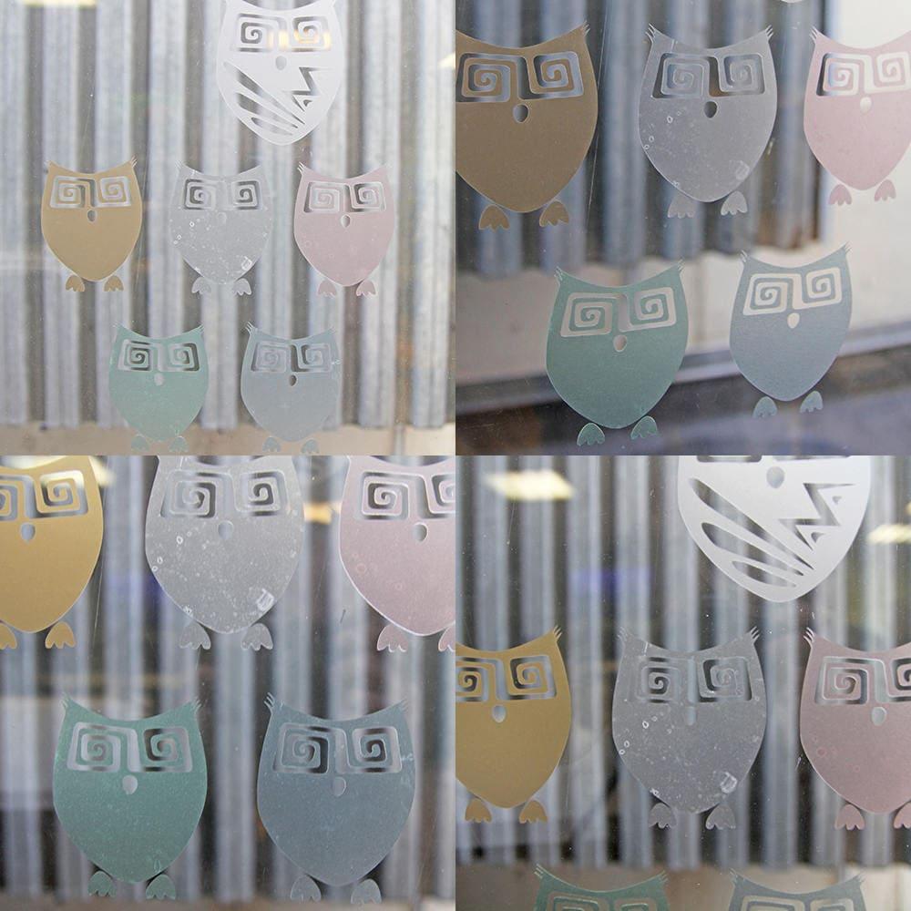 Custom frosted vinyl owl decals on a glass surface, featuring assorted pastel colors and playful designs.
