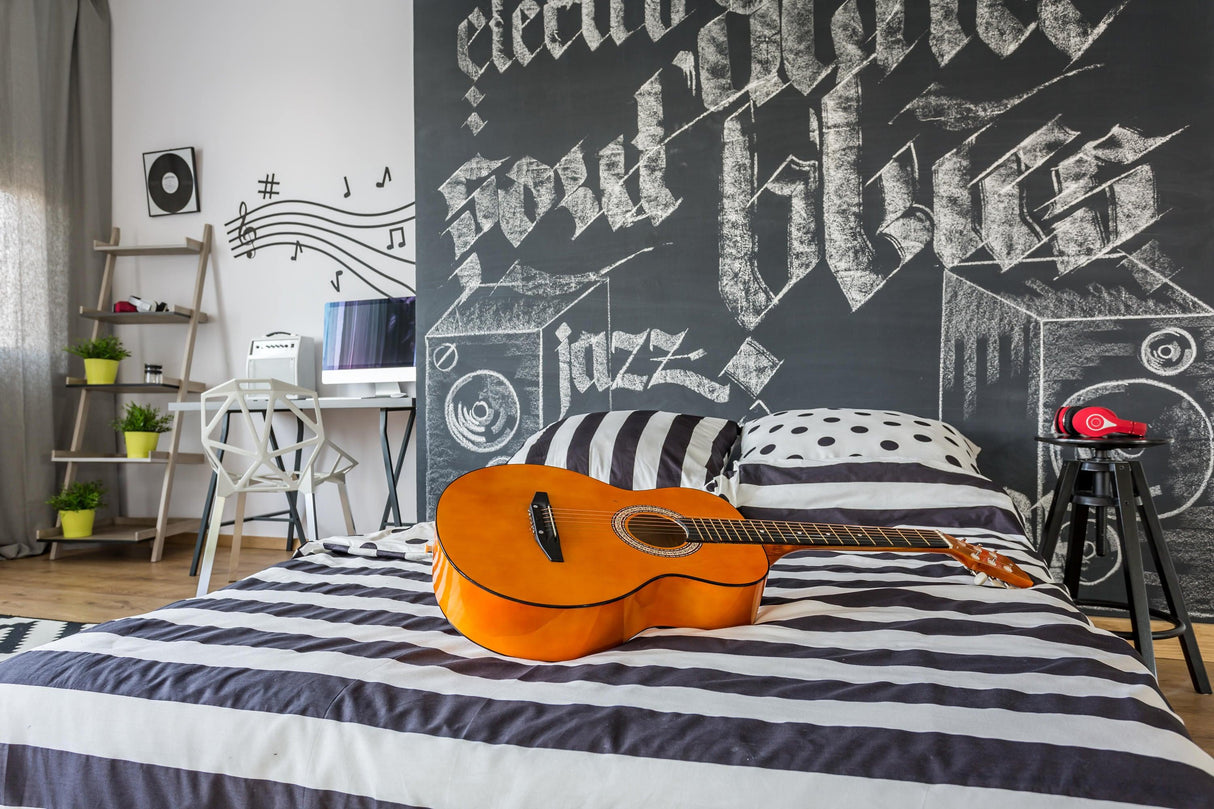 Stylish bedroom with black and white striped bedding, acoustic guitar on bed, and music-themed chalkboard wall decor.