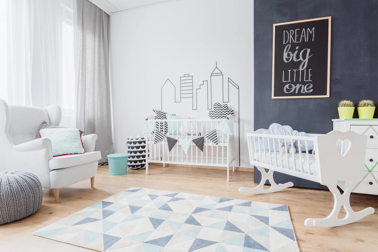 Stylish nursery with cribs, geometric rug, and motivational wall art for a cozy baby space.