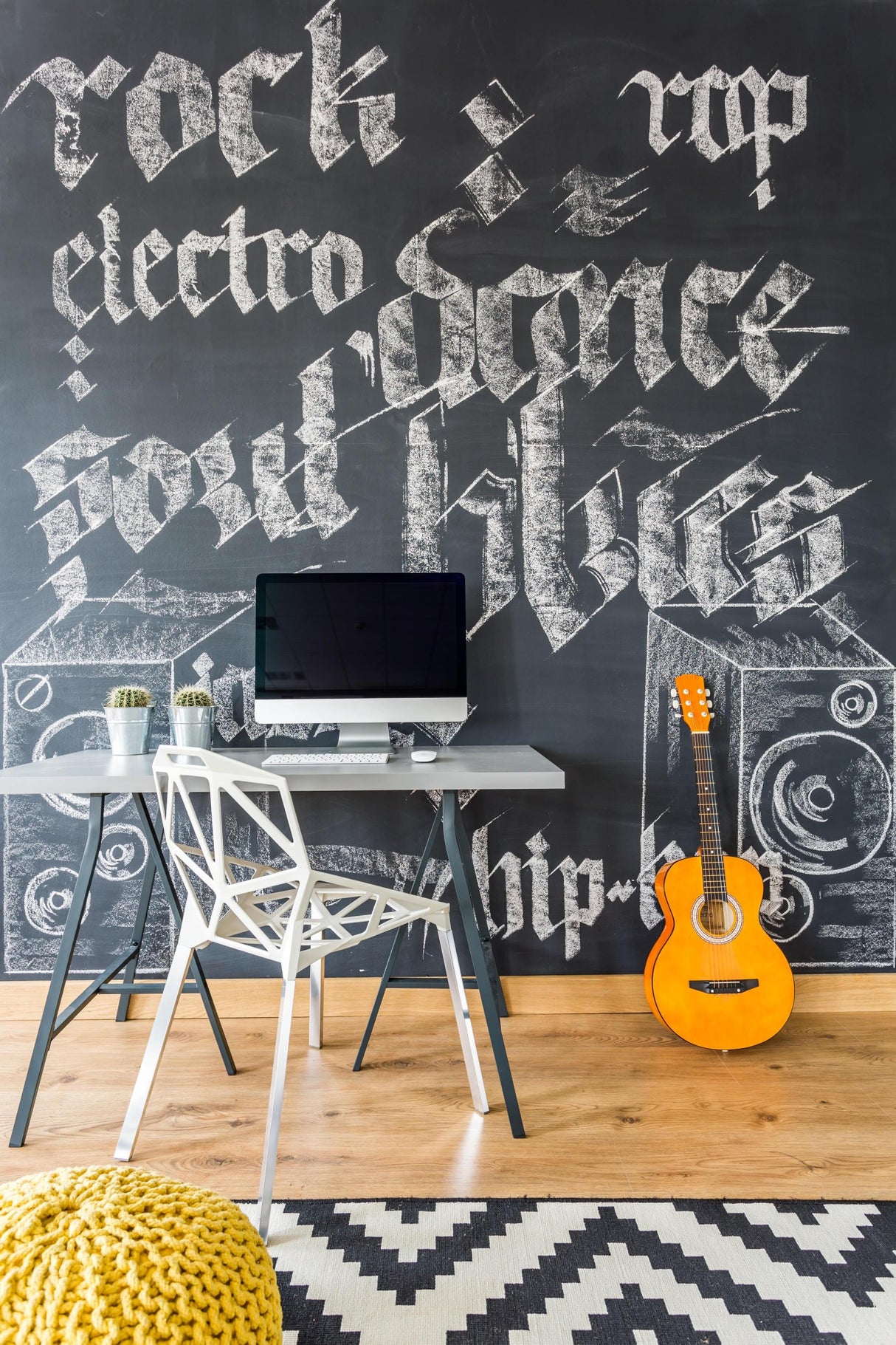 Chalkboard wall with music-themed artwork in a modern workspace featuring a desk, laptop, guitar, and stylish decor.