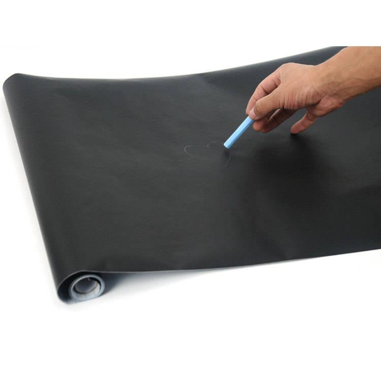 Hand writing on a black chalkboard wall sticker with blue chalk, showcasing its usability for decor or notes.