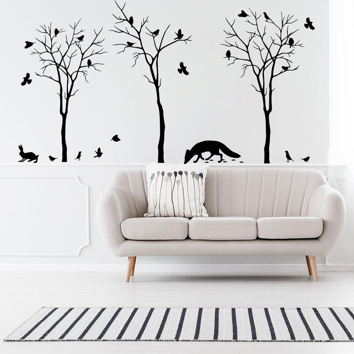 Elegant wall decals of trees and animals in a cozy living room with a modern sofa and striped rug.
