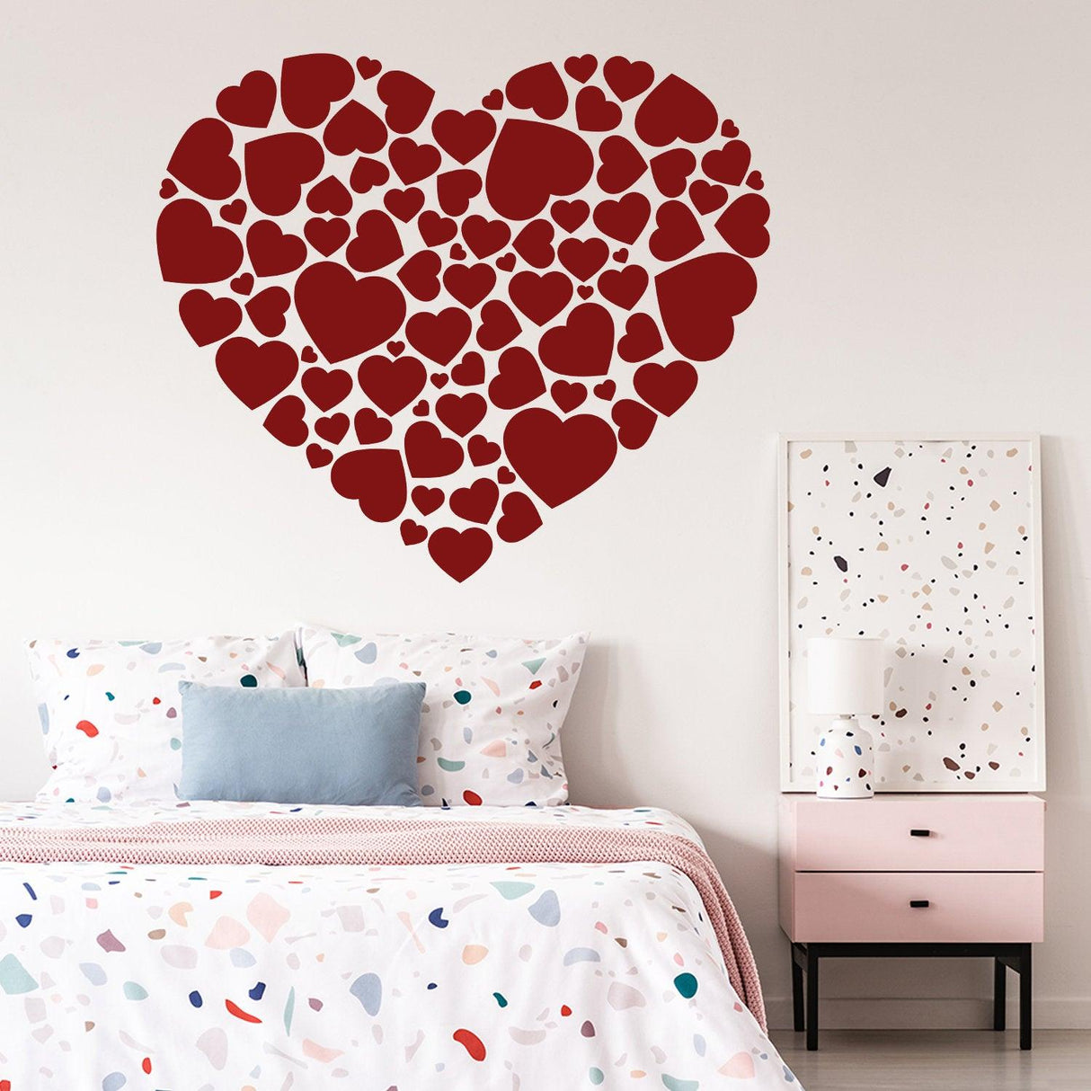 Heart sticker art vinyl decal with mini heart designs on a feature wall above a colorful bedspread.