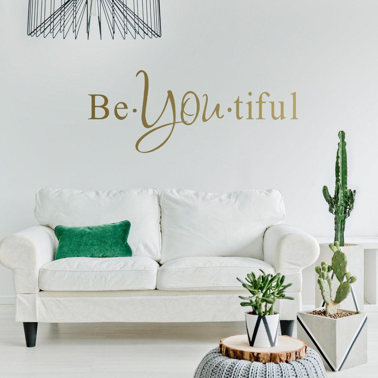 Stylish living room featuring 'Be You tiful' wall sticker above a white sofa with plants and decorative elements.