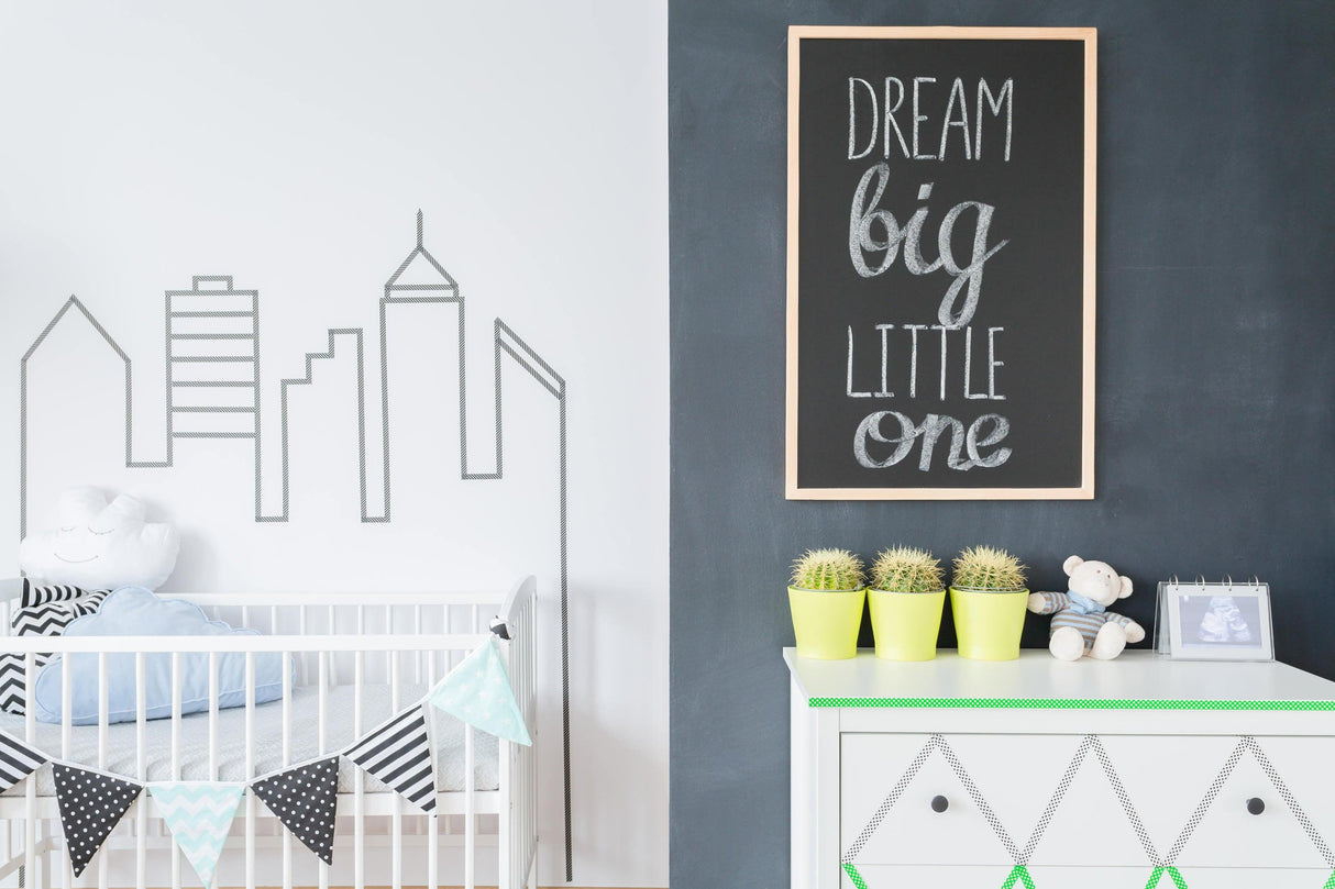 Modern nursery with skyline wall art and chalkboard sign reading 'Dream big little one'.