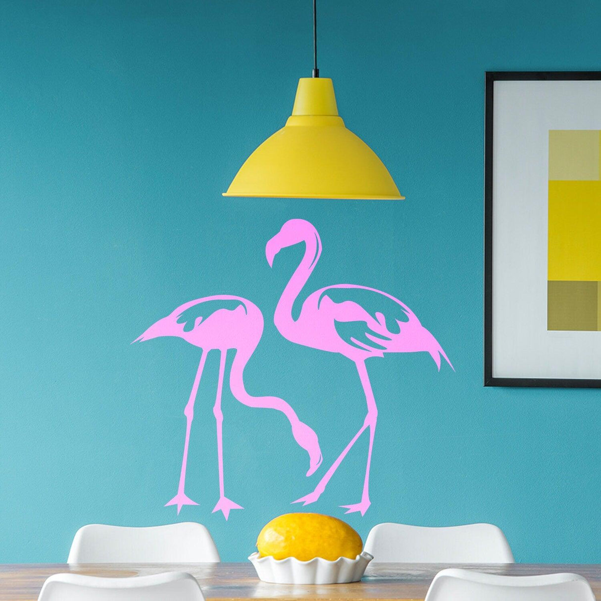 Pink flamingo vinyl decal on a turquoise wall above a dining table with a yellow pendant lamp.