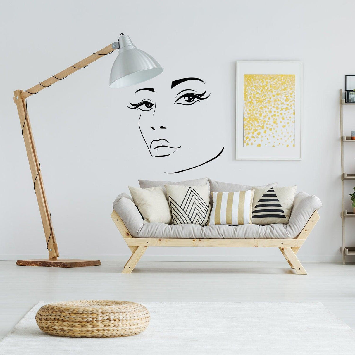 Elegant black vinyl sticker of a woman's face on a light wall above a cozy sofa, enhancing modern home decor.