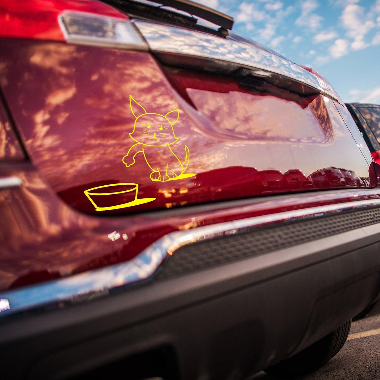 Cute yellow cat vinyl sticker on a red car's bumper, reminding drivers to fill their gas tank.