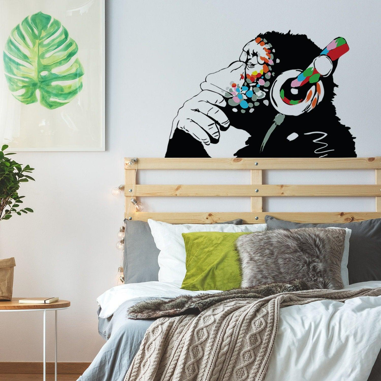 Banksy Thinking Monkey Sticker wall decal in a stylish bedroom, featuring a monkey with headphones and colorful accents.