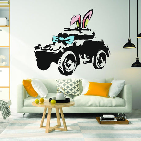 Banksy-style armoured car wall art sticker with bunny ears and bowtie on a modern living room wall.